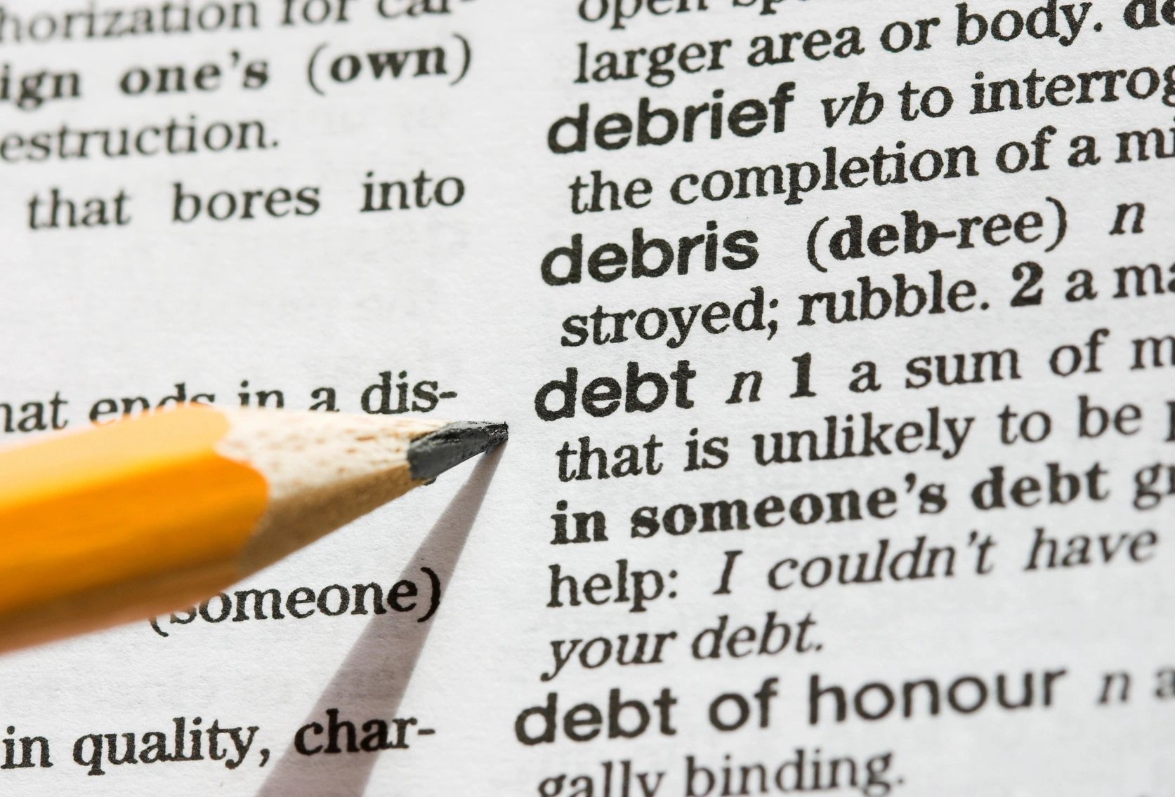 Pencil pointing to debt definition in dictionary